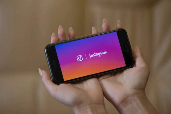 Женщины держат в руках мобильный телефон со стартовой страницей Instagram — стоковое фото