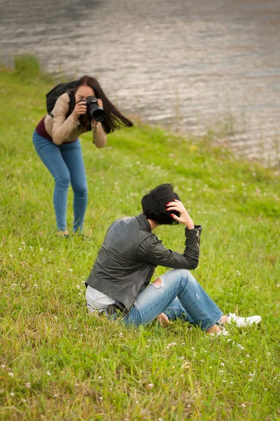 Jovem fotógrafa fazendo uma sessão de fotos com modelo ao ar livre — Fotografia de Stock