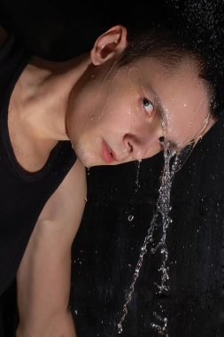 Karanlık arka plandaki adamın üzerine akan su.