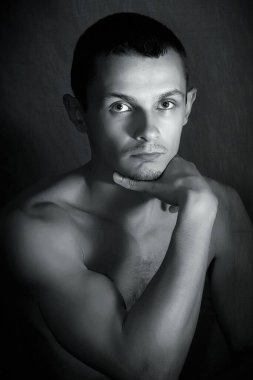 Karanlık arka planda düşünceli güçlü bir genç.