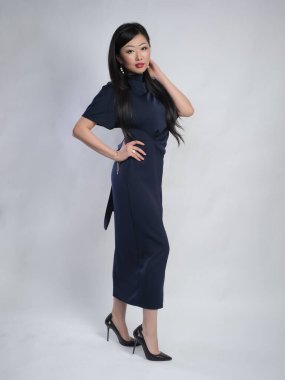 Stüdyoda beyaz arka planda poz veren uzun elbiseli Asyalı kadın model.