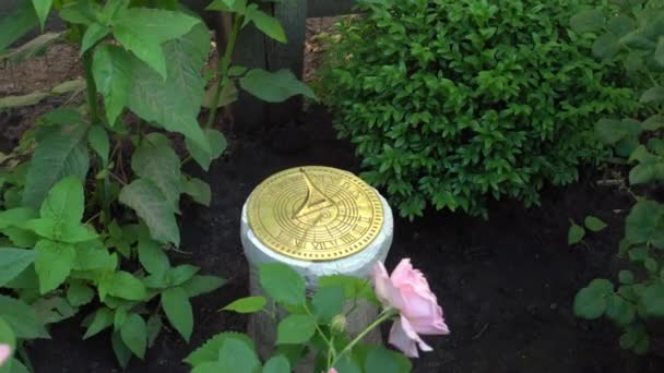 Primer plano del reloj de sol en un jardín inglés sobre fondo de rosas — Vídeos de Stock