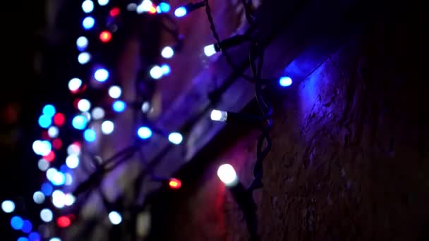 Primer plano borroso luces intermitentes blancas, azules y rojas de la guirnalda en el puesto del mercado de Navidad — Vídeos de Stock