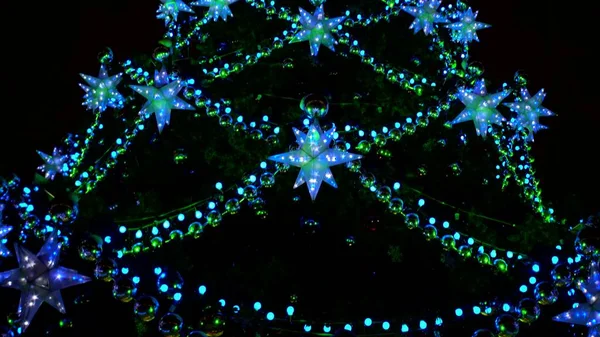 Majestueuse fabuleuse ville sapin de Noël en carré brillant avec des lumières vertes, bleues et jaunes de guirlandes, boules et étoiles — Photo
