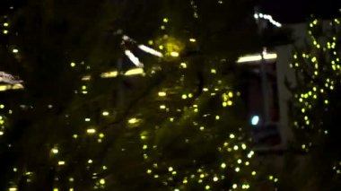 Küçük şirin Noel ağaçları Noel pazarında süslenmiş sarı parlak çelenkler arka planda dans ediyor.