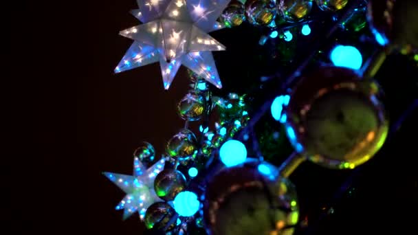 Gros plan de grandes boules jaunes sur fond d'étoiles bleues multi-pointes lumineuses floues et décoration sur la place des sapins de Noël sur la place du marché de Noël — Video