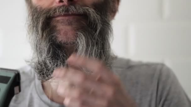 O homem de meia-idade de barba meio-cinza longo olha para o resultado do corte pelo cortador de cabelo — Vídeo de Stock
