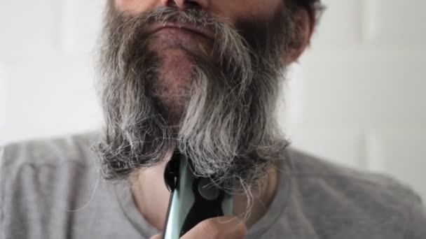 Középkorú férfi borotválkozás le egy darab félősz szakáll elektromos hajvágó — Stock videók