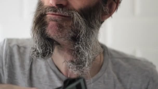 Muž středního věku vede elektrický střihač zdola až po oholený kus vousu — Stock video