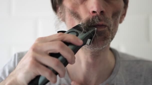 Man van middelbare leeftijd scheert snor en lange baard resten af aan de rechterkant — Stockvideo
