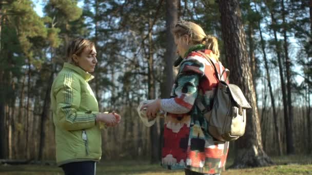 Kaksi keski-ikäistä naista laittaa roskat muovipussiin metsäaukiolla — kuvapankkivideo