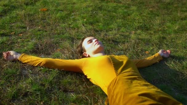 Jong mooi meisje ligt op gazon in bos, niest en glimlacht — Stockvideo
