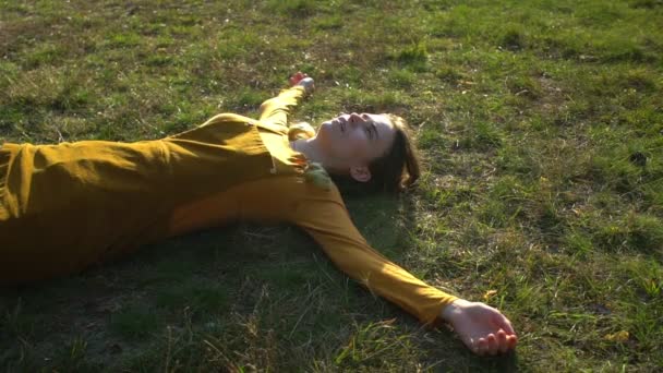 Detailní záběr mladé krásné ženy ve žlutých šatech leží na trávníku v podzimním lese — Stock video