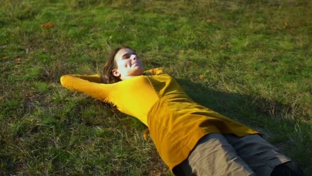 Jovem menina bonita se levanta do gramado na floresta — Vídeo de Stock