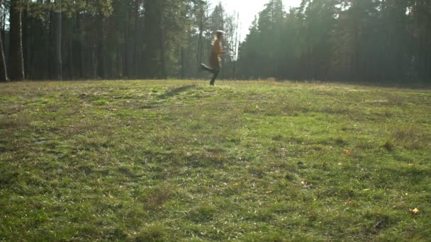 Jeune belle femme en robe jaune court sur la pelouse dans la forêt d'automne — Video