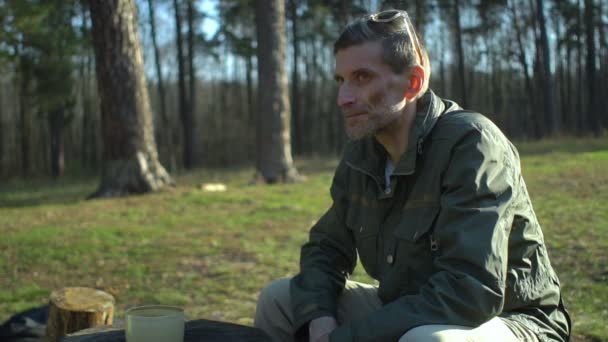 Uomo di mezza età che beve caffè dalla tazza bianca sul prato fondo della foresta autunno — Video Stock