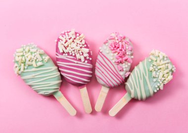 Farklı pasta pembe bir arka plan üzerinde sopa buzlu çubuk şeklinde açılır. Üstten görünüm.