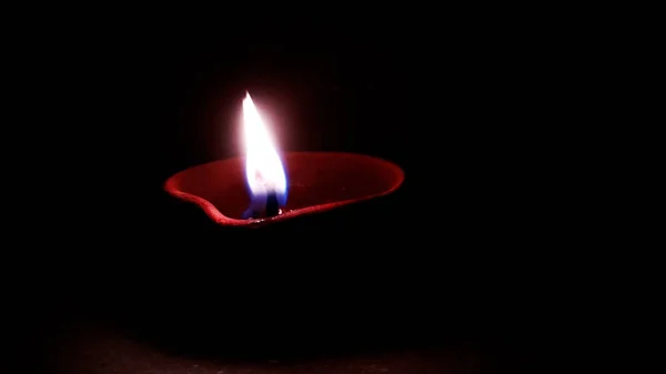 Imagen de cerca de una diya de arcilla encendida o una lámpara en el suelo en Diwali - un festival hindú indio de luces aisladas sobre fondo negro . — Foto de Stock