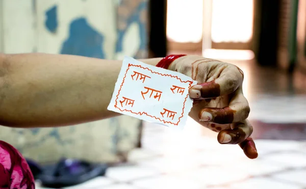 A lady holding a piece of paper with name of lord ram written on it on the occasion of raksha bandhan.