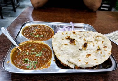 Geleneksel bir Kuzey Hint restoranı. İçinde taze pişmiş naan ve kişniş ile süslenmiş iki kase baharatlı köri var.