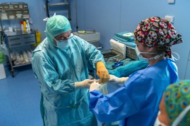 Ameliyathane asistan cerrah steril eldiven koyarak yardım. Sen-ebilmek görmek onları kadar koyarak onların steril eldiven