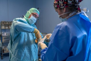 Ameliyathane asistan cerrah steril eldiven koyarak yardım. Sen-ebilmek görmek onları önünde koyarak onların steril eldiven