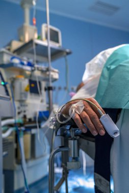 Hastanın el bir serum ve bir oksijen doygunluğu metre üstünde parmak. Monitör ve arkadaki bütün telleri ile solunum.