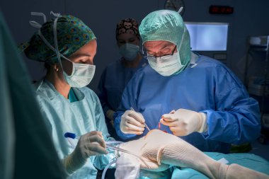 Cerrah, cerrahi asistanı ve ameliyat odasında çalışan hemşire cerrahi malzeme görebilirsiniz. Onlar işletim Oda ışıkla aydınlatılmış.