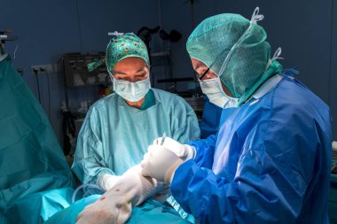 Cerrah, cerrahi asistanı ve ameliyat odasında çalışan hemşire cerrahi malzeme görebilirsiniz. Onlar işletim Oda ışıkla aydınlatılmış.