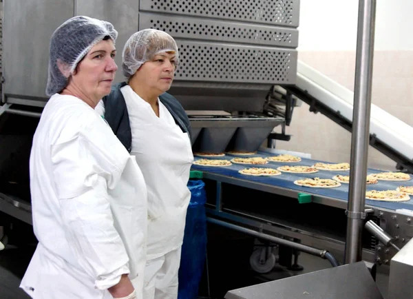Moskova, Rusya - Ocak 2012: Pizza ve iki fırın işçileri konveyör. Pastane Moskova'da fabrika.