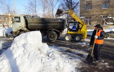 Moskova, Rusya - Ocak, 2015: Sarı mini traktör, işçi ve damperli kamyon. Şehrin sokaklarında kışın Moskova'da temizlik..