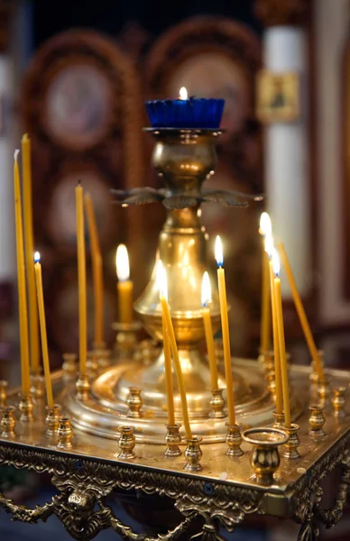 Candles and a lamp on a gilded candlestick, the interior of an Orthodox church.