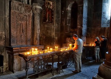 Erivan, Ermenistan - Eylül, 2018: Bir adam tapınağın bir mum yanar. Geghard Manastırı bir ortaçağ manastır Ermenistan'da Kotayk il mi,