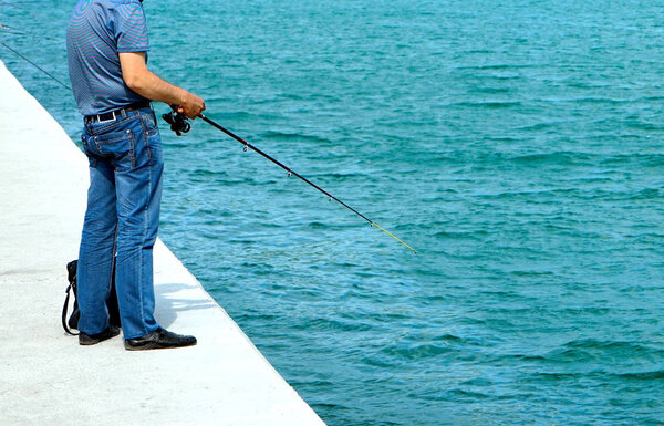 The man on the dock with a fishing rod, catches fish.
