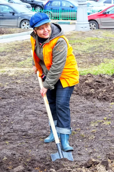 モスクワ 2016 シャベル オレンジ色のベストの女性は地面を掘っていきます 街の清掃 — ストック写真