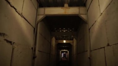 Beton duvarlar, loş elektrik aydınlatma ile karanlık bir koridor boyunca hareket.