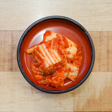 Ahşap bir masa üzerinde kil levha içinde Kore kimchi.