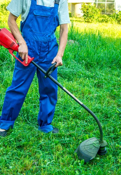 緑の草の上に芝刈り機を持つ男 — ストック写真