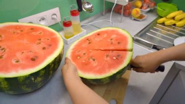 Karpuz kesmek. Mutfakta bıçaklı bir kadın büyük olgun kırmızı karpuz keser.