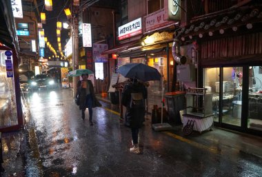 Seul - Mart 2019: gece yağmuru, insanlar şemsiye altında yürür. Yemek Sokağı, Tongin-dong.
