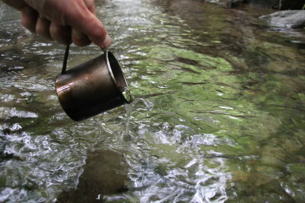 A mug of water in the background of a stream — Stock Photo, Image