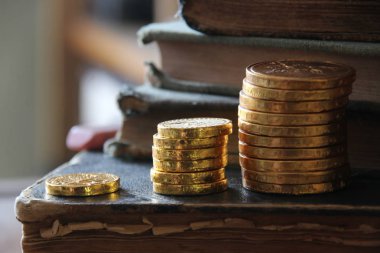 Para büyüme fikri. Altın sikke ve vintage kitap yığınları.