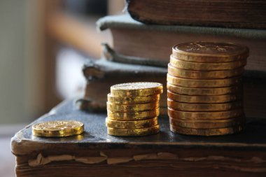 Para büyüme fikri. Altın sikke ve vintage kitap yığınları.