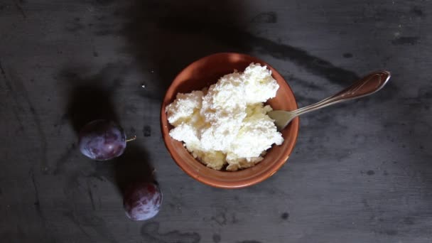 Fromage fermier, fromage caillé ou fromage cottage dans un bol sur table et prunes — Video