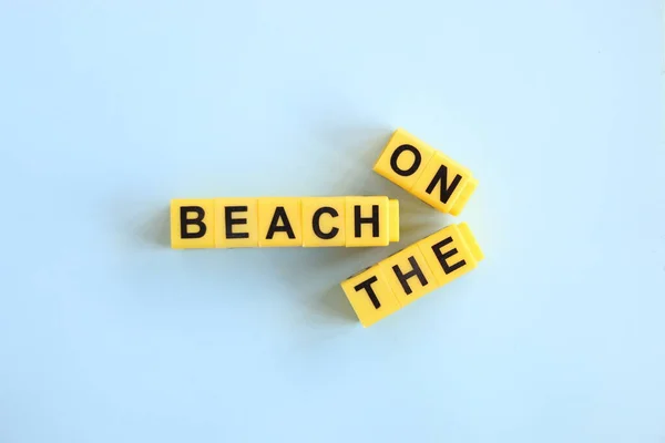 Na plážovém konceptu, nápis žlutými písmeny na modrém pozadí — Stock fotografie