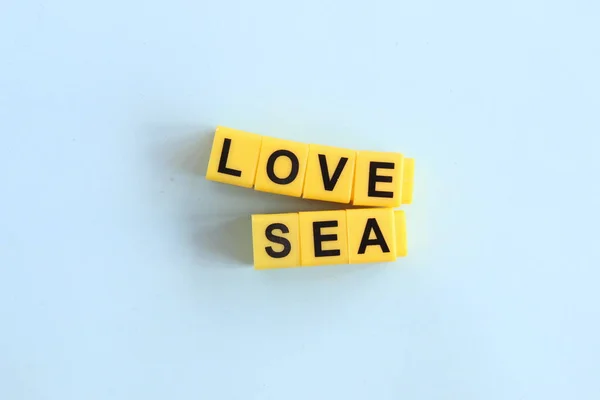 Szerelem tenger koncepció, felirat sárga betűkkel a kék háttér — Stock Fotó