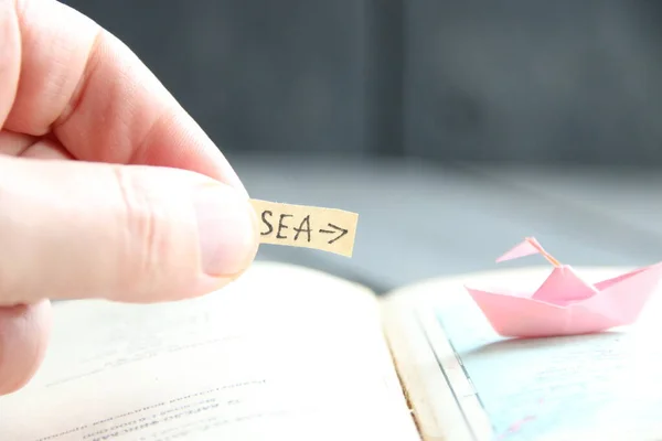 A mão segura um ponteiro para o mar e barcos de papel no mapa . — Fotografia de Stock