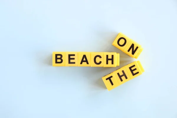 På stranden konceptet, inskrift med gula bokstäver på en blå bakgrund — Stockfoto