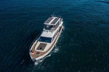 Güneş panelleri olan modern beyaz yolcu botu derin mavi deniz sularında geziniyor, lüks yatı gören hava aracı görüntüsü, deniz yolculuğu...