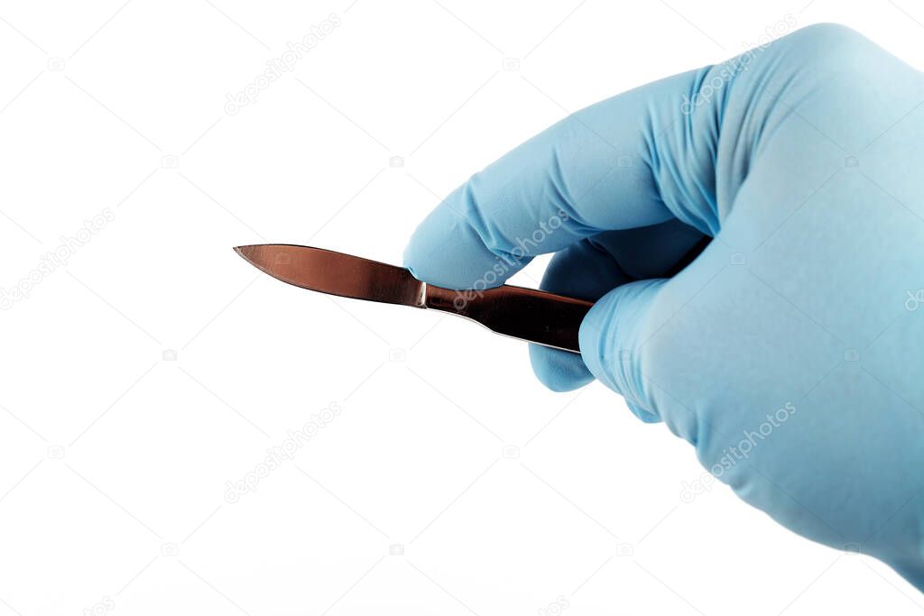 medical scalpel in the hand of a surgeon, white background, close-up
